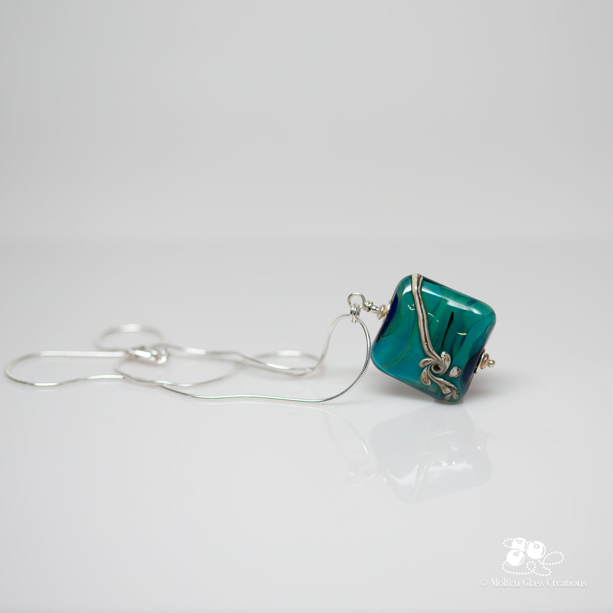 Teal Flourish Square Pendant - side view showing depth and gloss of teal lampwork glass square bead with fine silver wire wrap detail